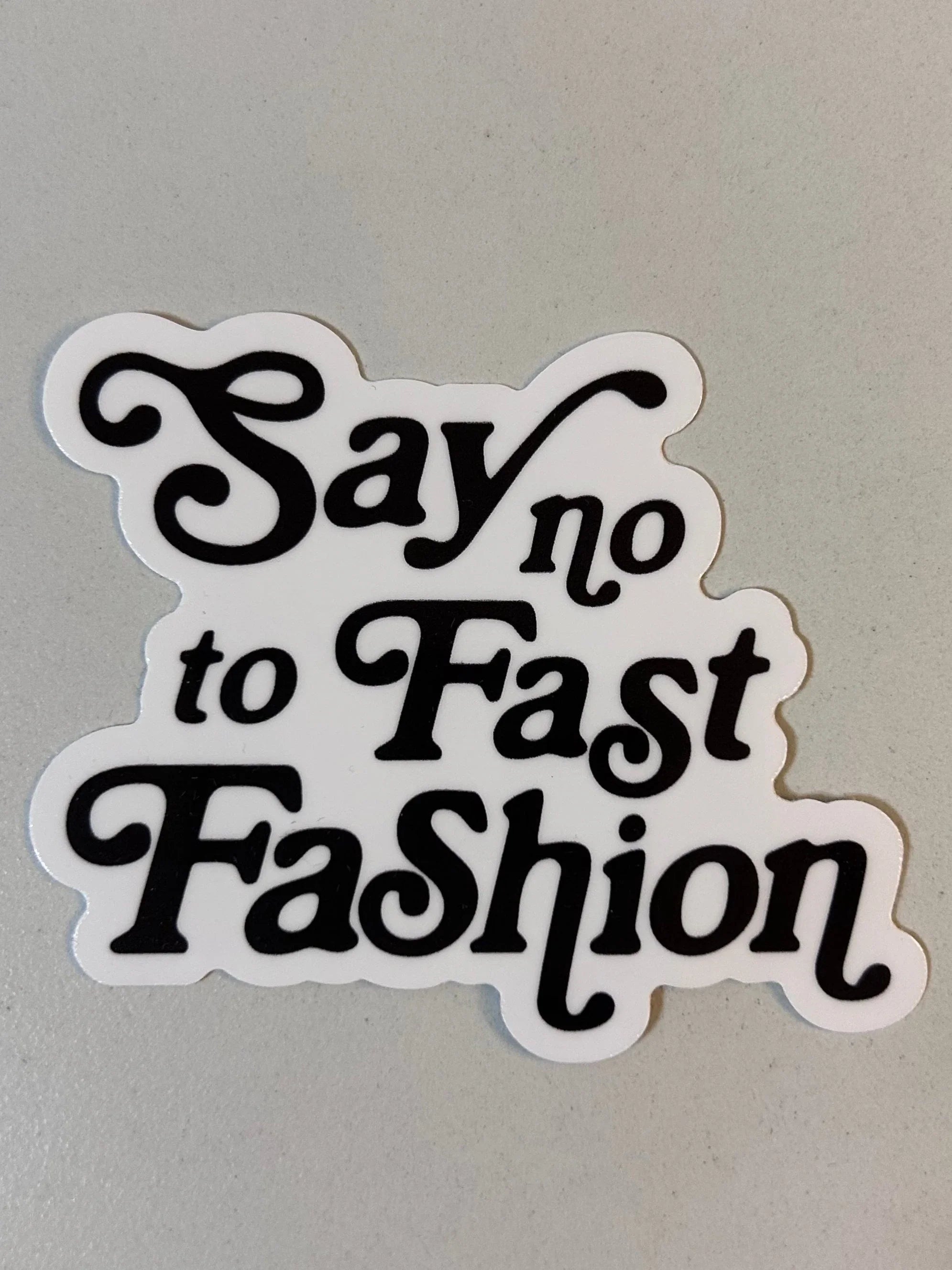 Sticker with retro text saying 'Say no to Fast Fashion' on a light surface, promoting sustainable style