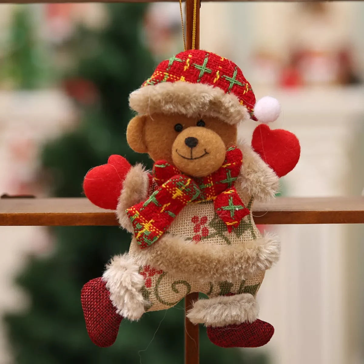 Christmas teddy bear ornament with red plaid hat, scarf, and heart-shaped mittens hanging on wooden cross