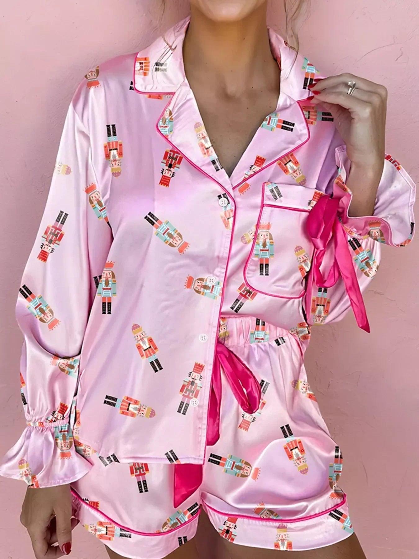 Woman wearing pink satin nutcracker print pajamas with button-up shirt and shorts