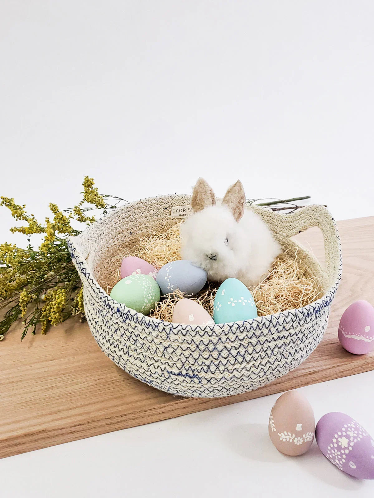 Handmade basket with faux bunny and pastel Easter eggs, styled by Qu!rk Boutique for spring decor.
