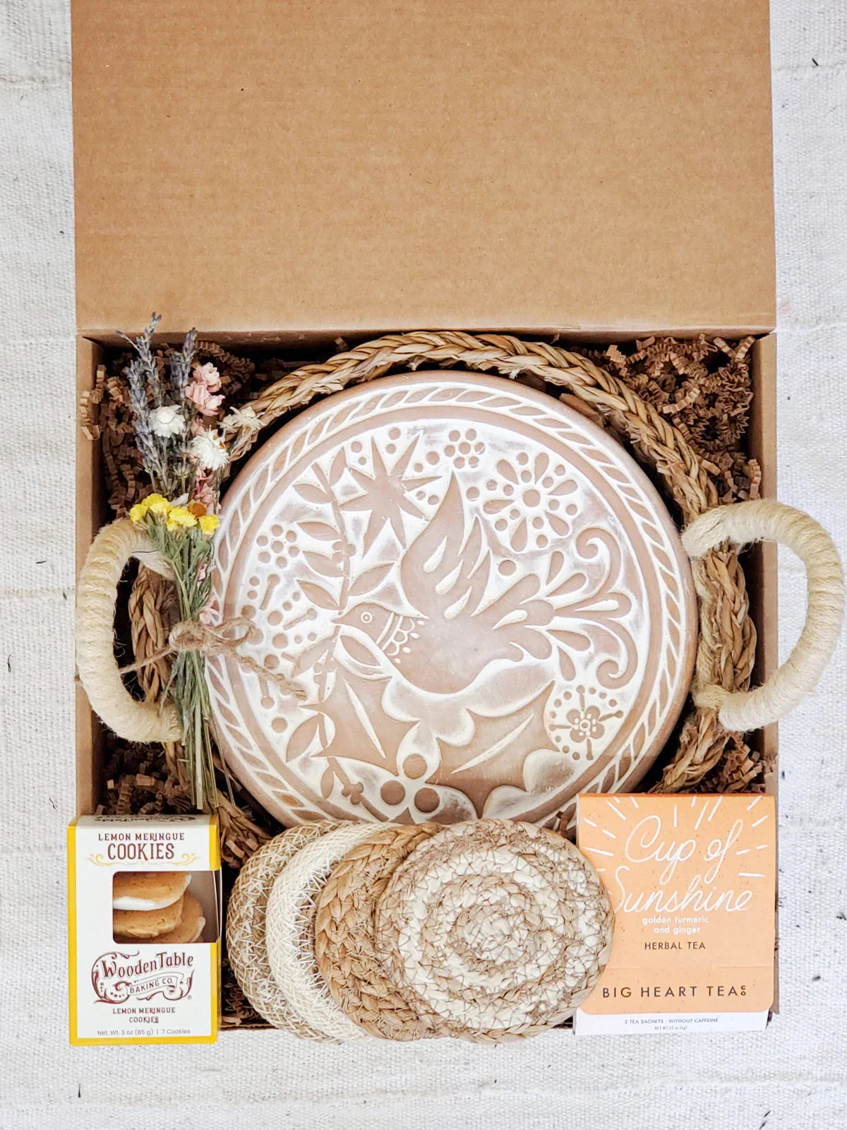 Gift box with decorated ceramic bird bread warmer, coasters, lemon meringue cookies, herbal tea, and dried flowers