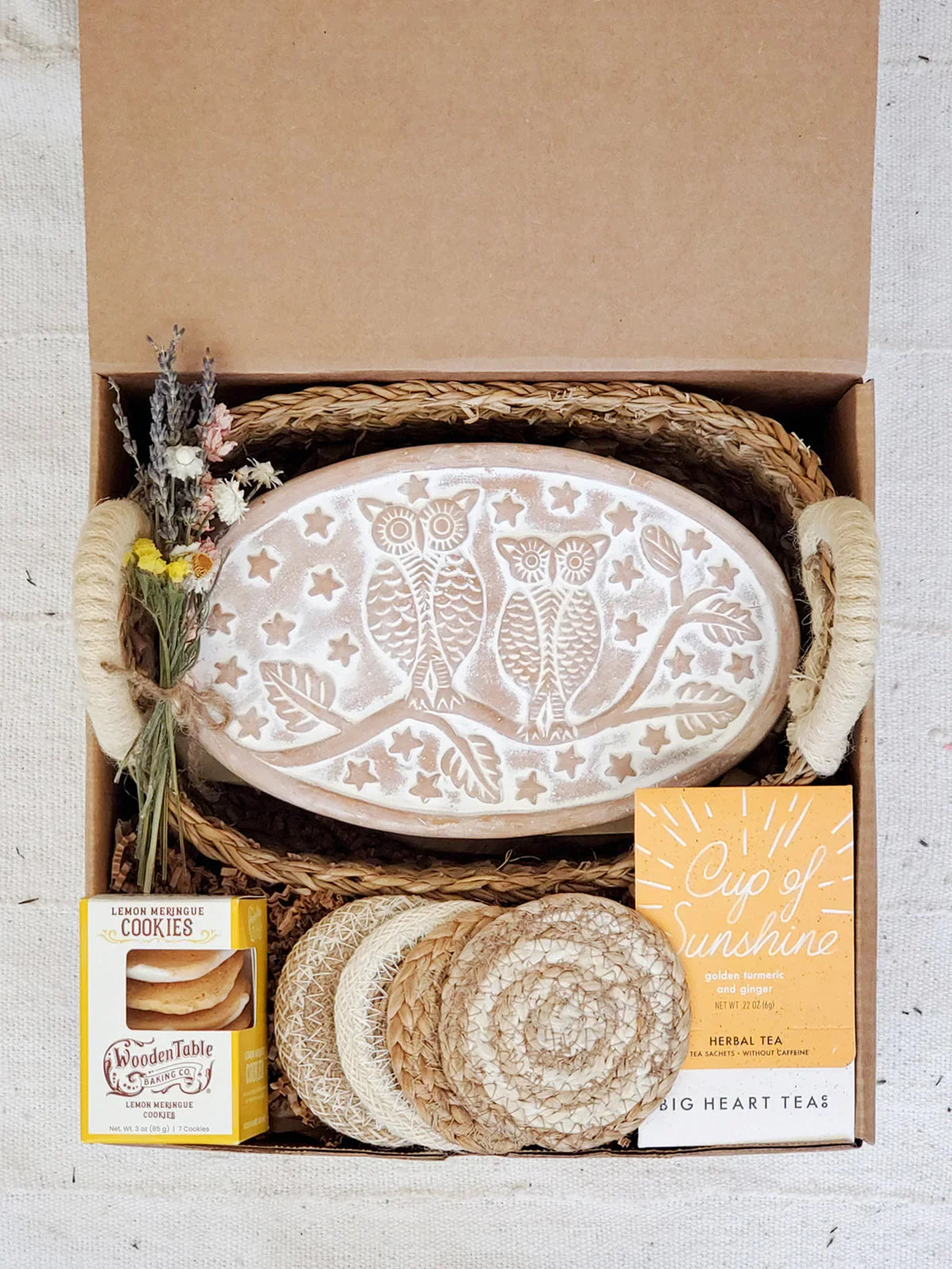 Gift box with owl engraved bread warmer, lemon cookies, herbal tea, woven coasters, and dried flowers