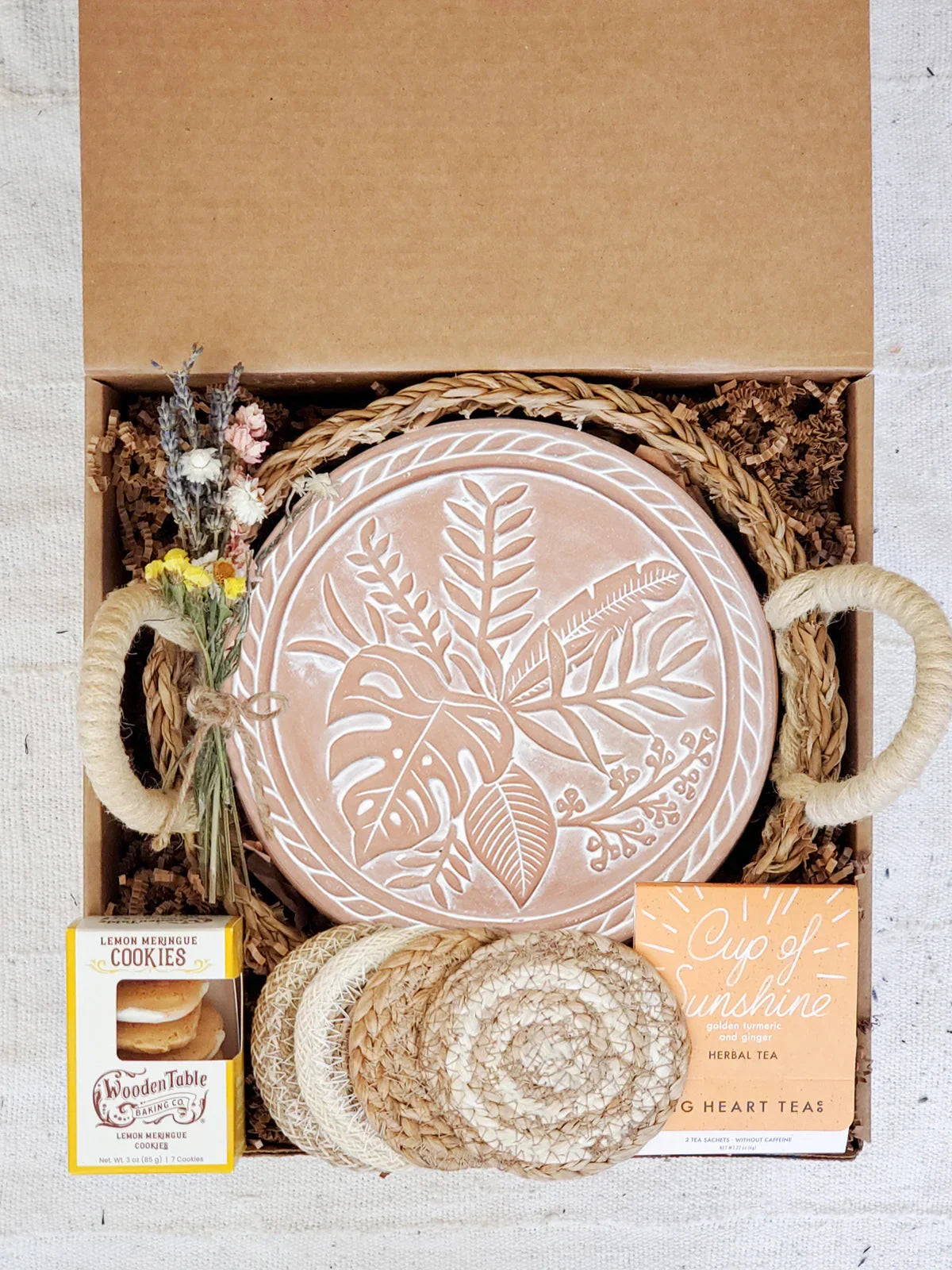 Gift box with terracotta plant-patterned bread warmer, woven coaster set, lemon cookies, herbal tea, dried flowers