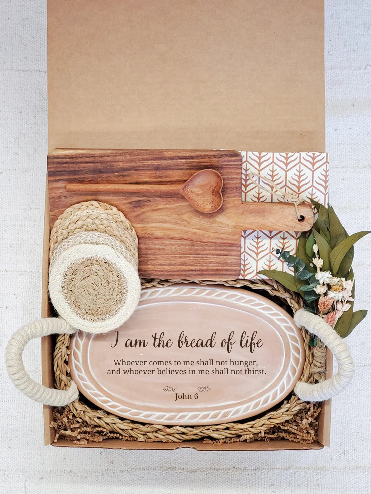 Gift box with decorative ceramic bread tray inscribed John 6 verse, wooden heart spoon, coasters, and dried flowers