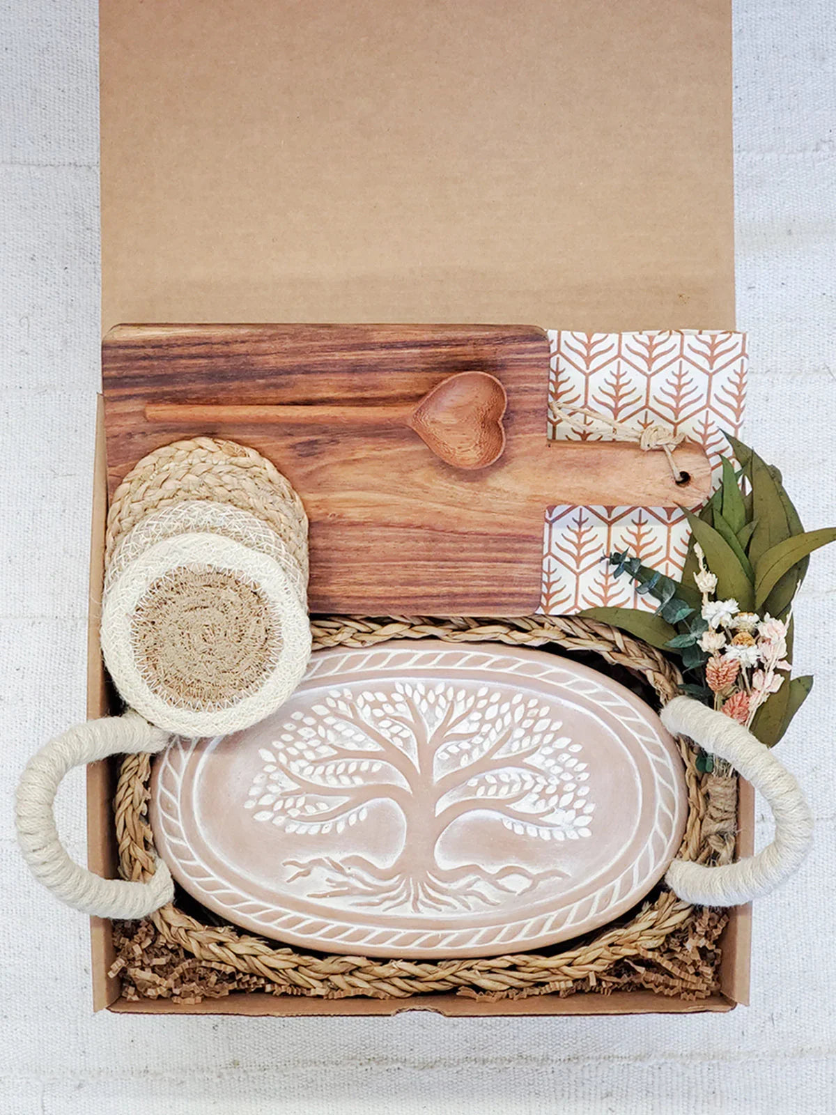 Oval ceramic bread warmer with tree design, wooden cutting board, heart-shaped spoon, and coasters in gift box