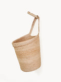 Natural woven hanging basket with single handle on a wooden peg, minimal eco home décor.