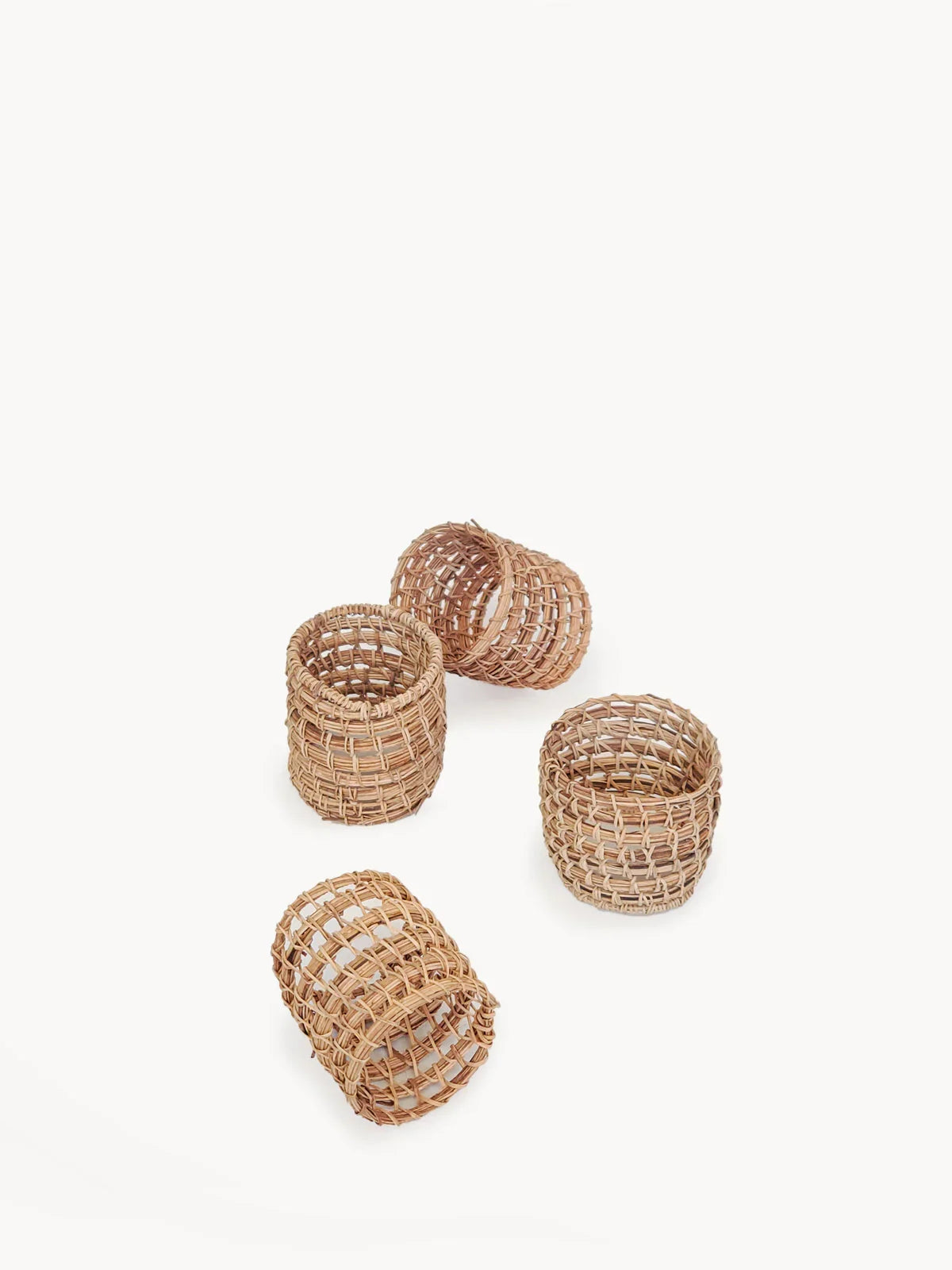 Set of four natural woven rattan napkin rings on white background