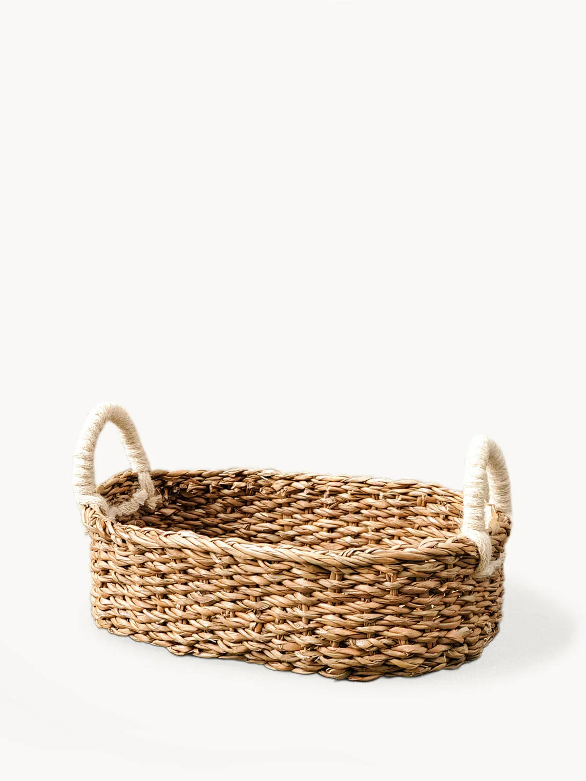 Oval woven bread basket with two rope-wrapped handles on white background