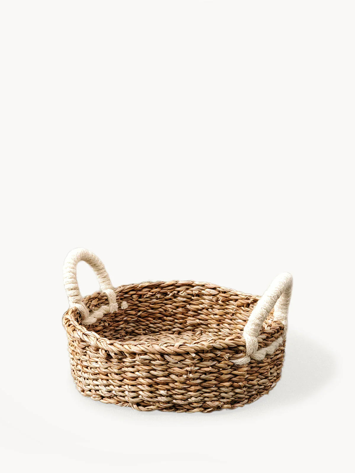Round woven bread basket with rope handles on white background