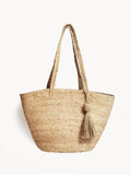 Natural woven shoulder bag with long handles and a decorative tassel, eco-friendly style
