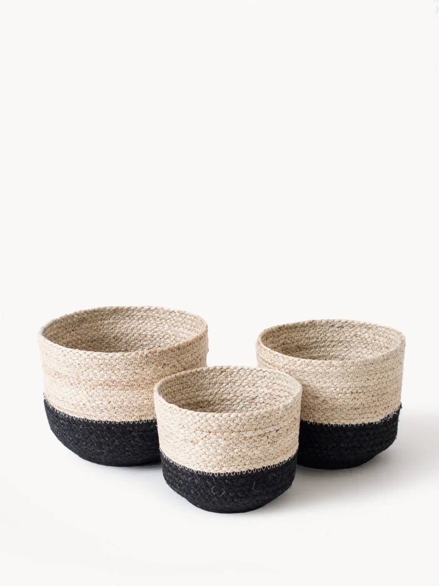 Set of three woven storage baskets with natural beige and black color blocks on white background