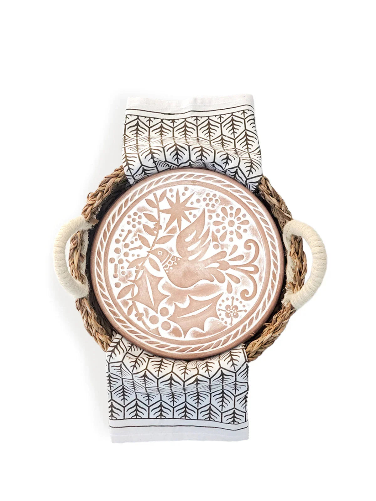 Round terracotta bread warmer with bird and floral design, in woven tray with patterned tea towel