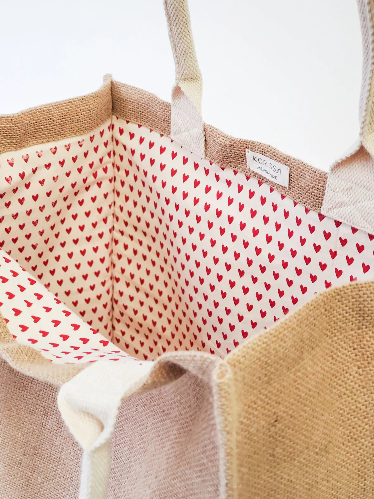 Handmade beige jute market bag with cream cotton lining and red heart pattern inside