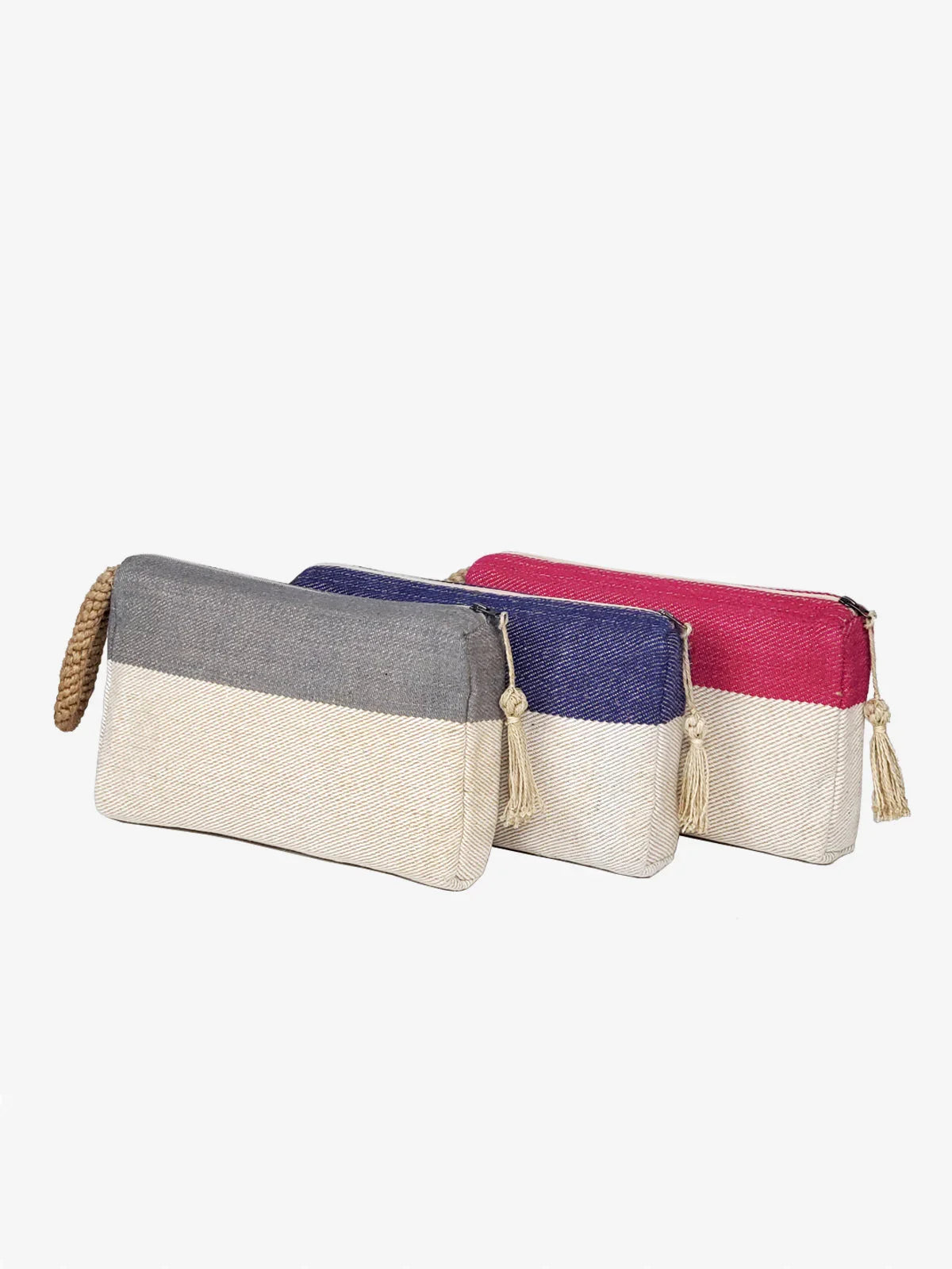 Three two-tone fabric clutch bags in gray, blue, and pink with white bases and tassel zippers