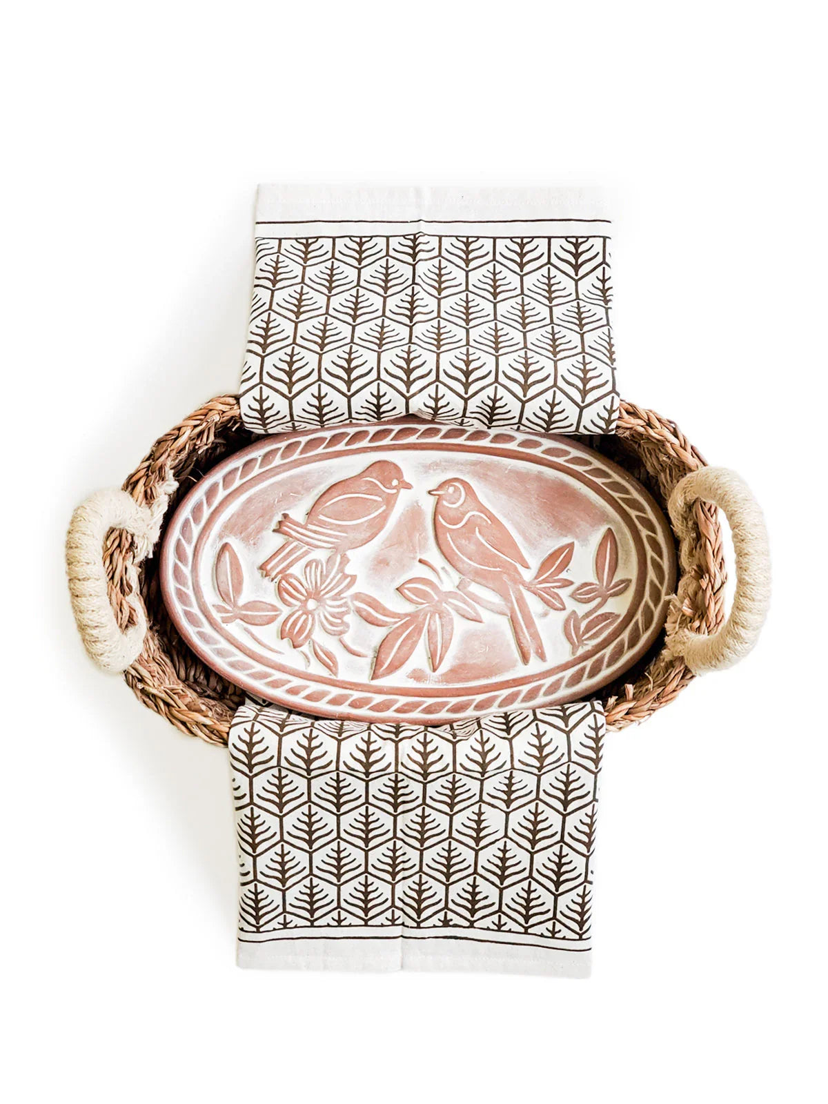 woven bread warmer basket with handles, oval clay plate featuring lovebird design, and patterned tea towel