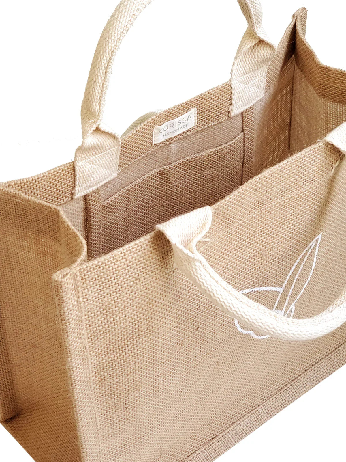 Natural beige jute tote bag with white handles and a small interior pocket, handmade label visible