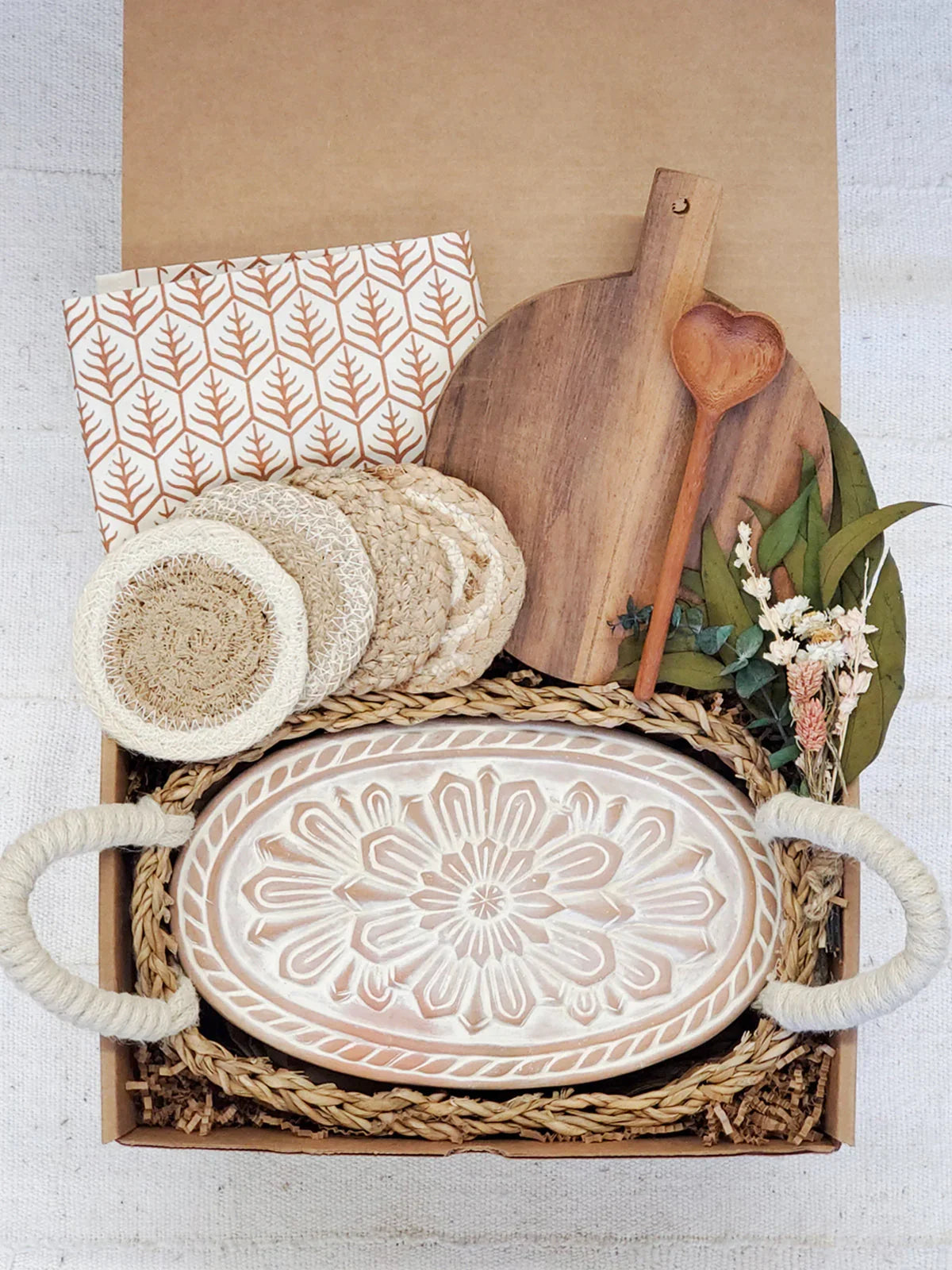 Eco-friendly gift box with carved ceramic bread warmer, wooden board, coasters, heart spoon, and dried florals