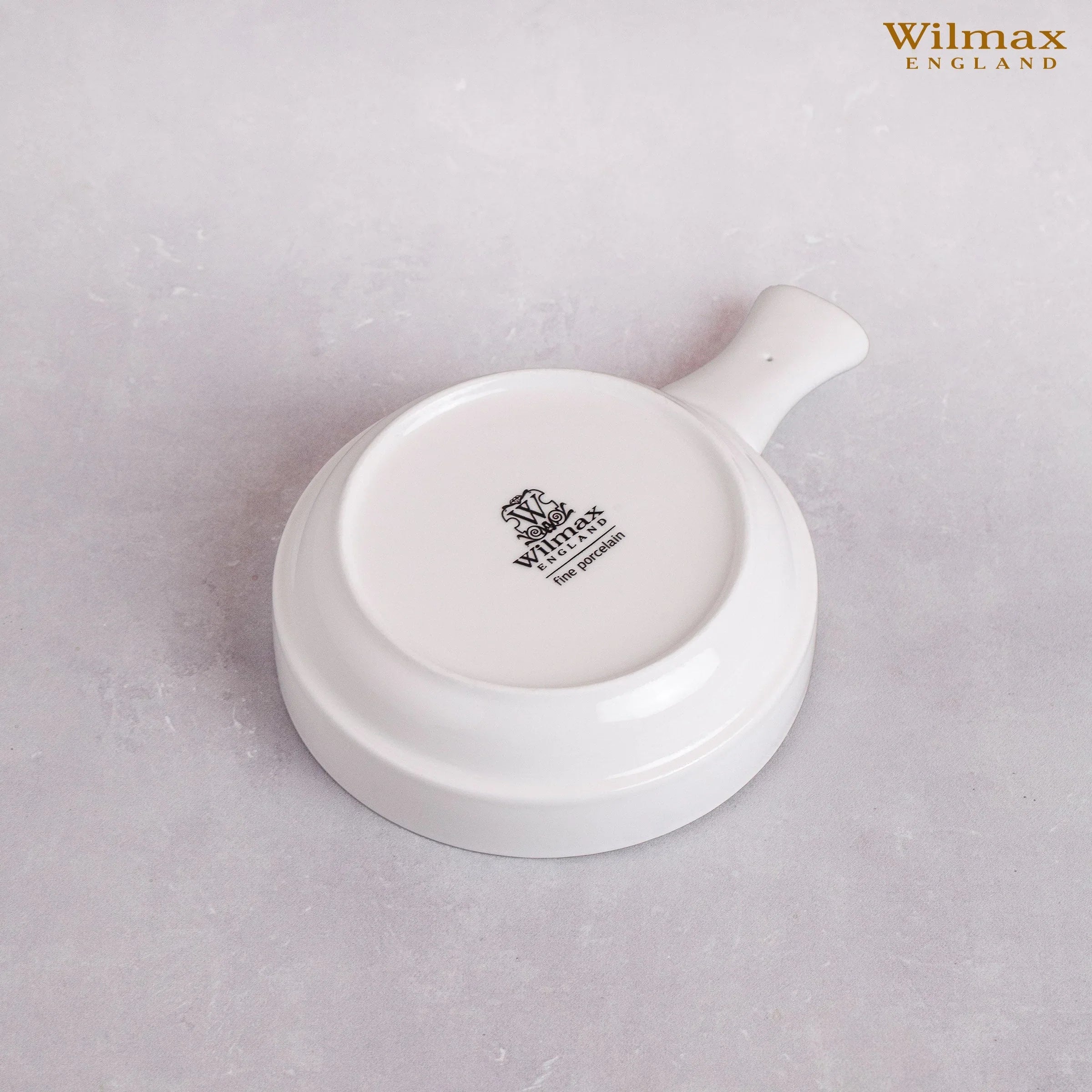 White Wilmax England fine porcelain dish with handle, shown upside down on a light gray surface.
