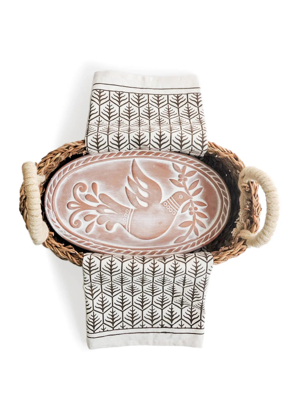 Oval bread warmer with dove design in a wicker basket with patterned cloth on white background