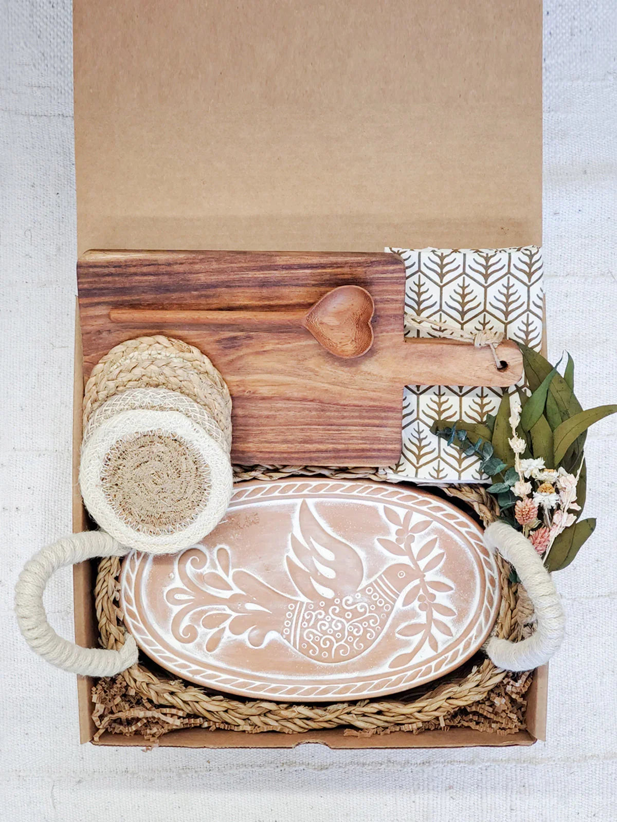Gift box with ceramic bird platter, wooden heart spoon, cutting board, coasters, and dried flowers