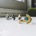Artist-designed gold and silver rings with gemstone inlays on white surface at Qu!rk Boutique