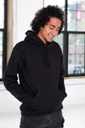 Model wearing a black hoodie from Qu!rk Boutique in a bright, modern indoor setting.