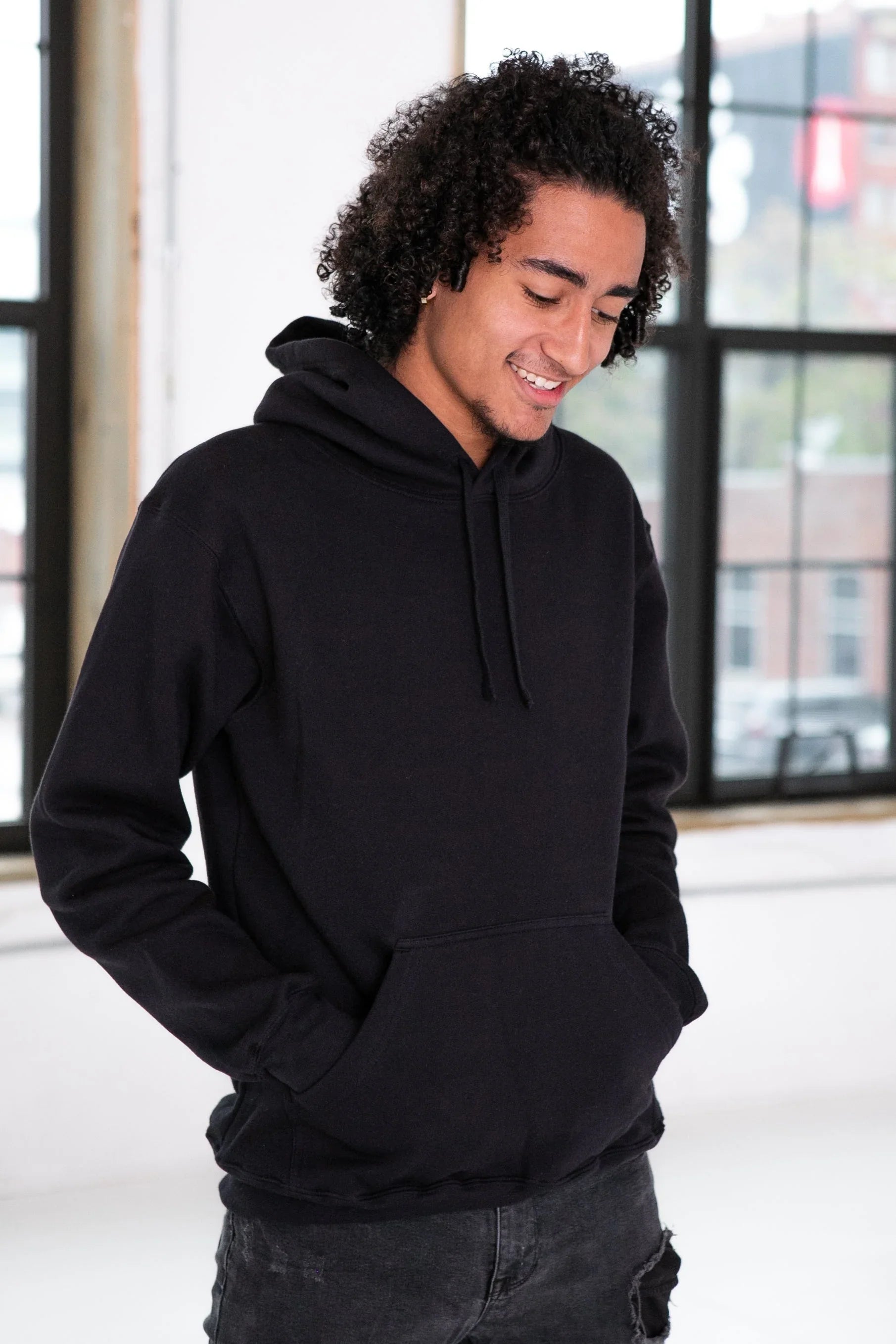 Model wearing a black hoodie from Qu!rk Boutique in a bright, modern indoor setting.