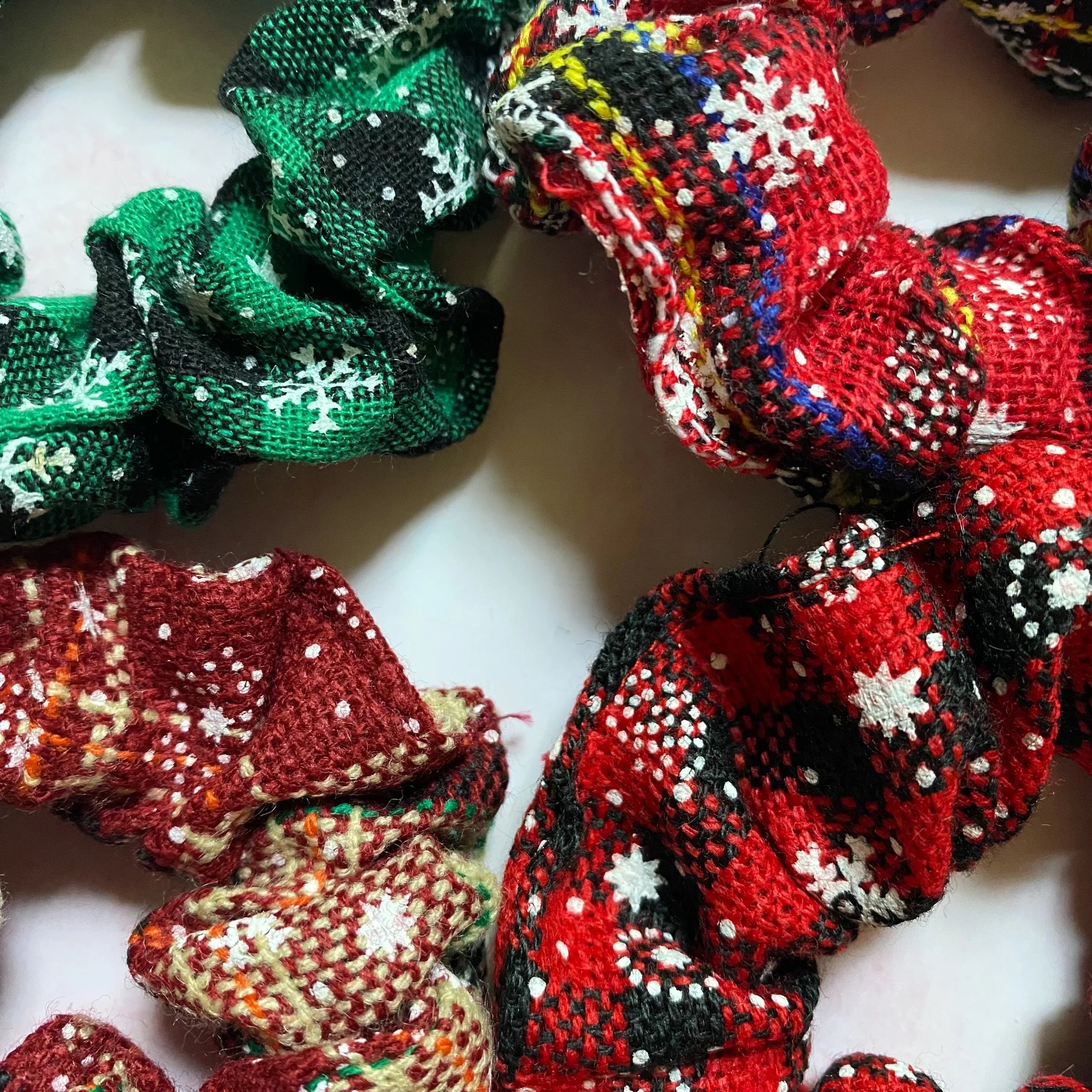 Close-up of cozy winter fabric scrunchies in red, green, and brown with snowflake patterns