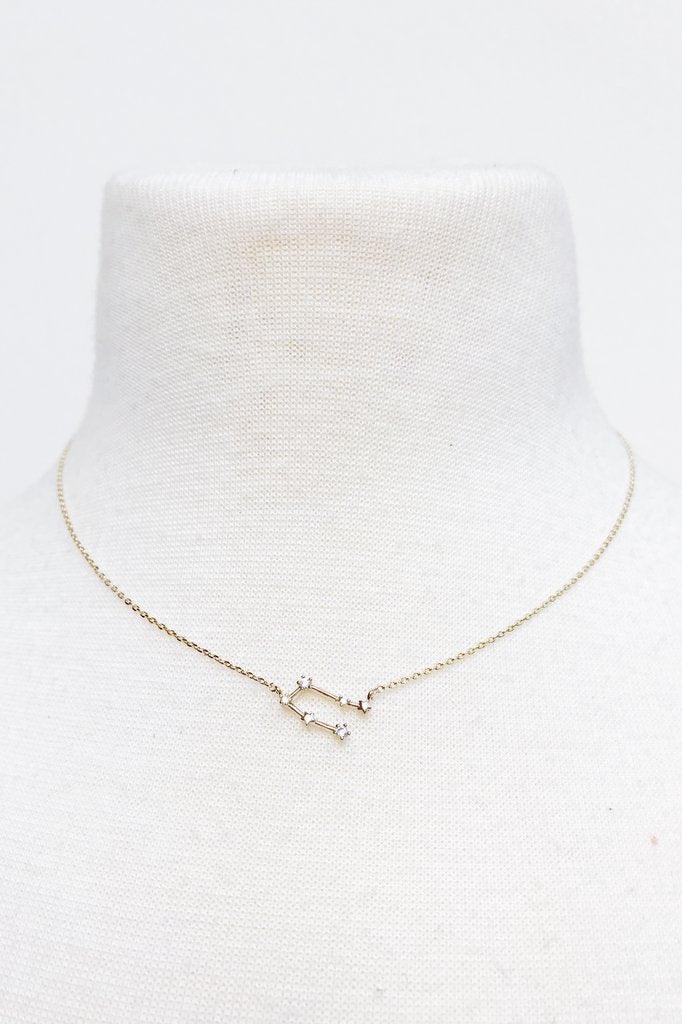 Delicate gold constellation necklace with star accents on white fabric display bust