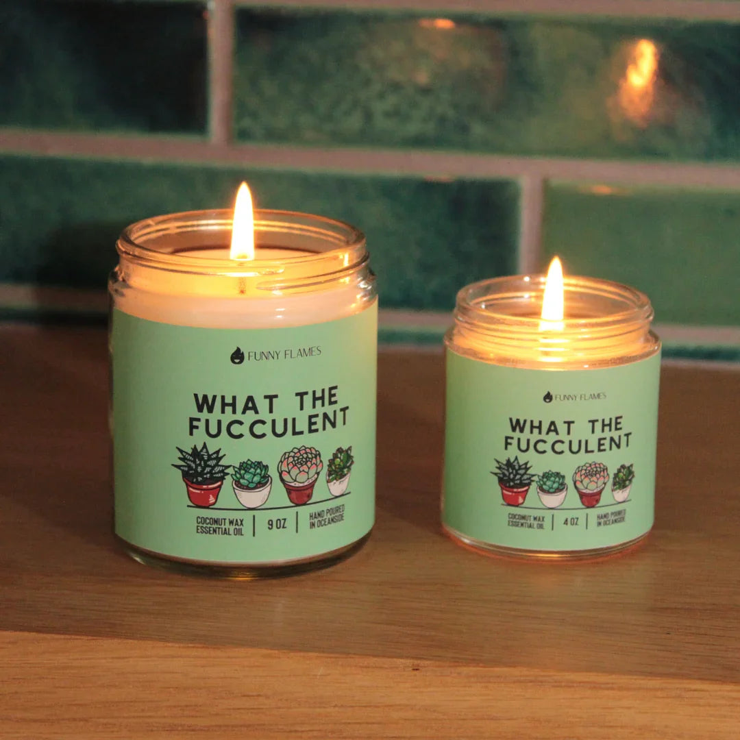 Two lit Funny Flames scented candles labeled What The Fucculent with succulent plant illustrations