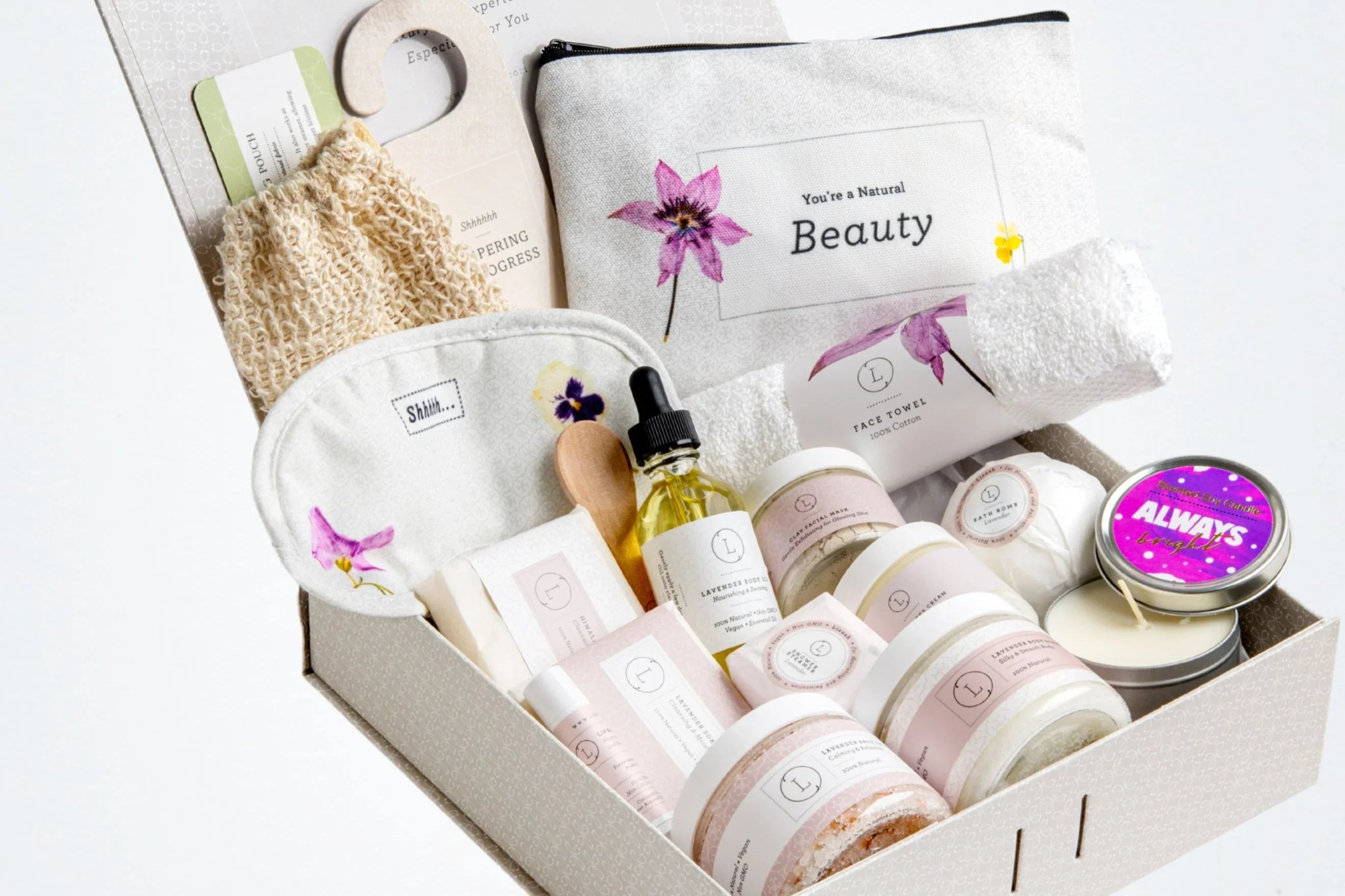 Gift box with natural beauty spa products including lavender oil, face towel, clay mask, candle, and bath bomb
