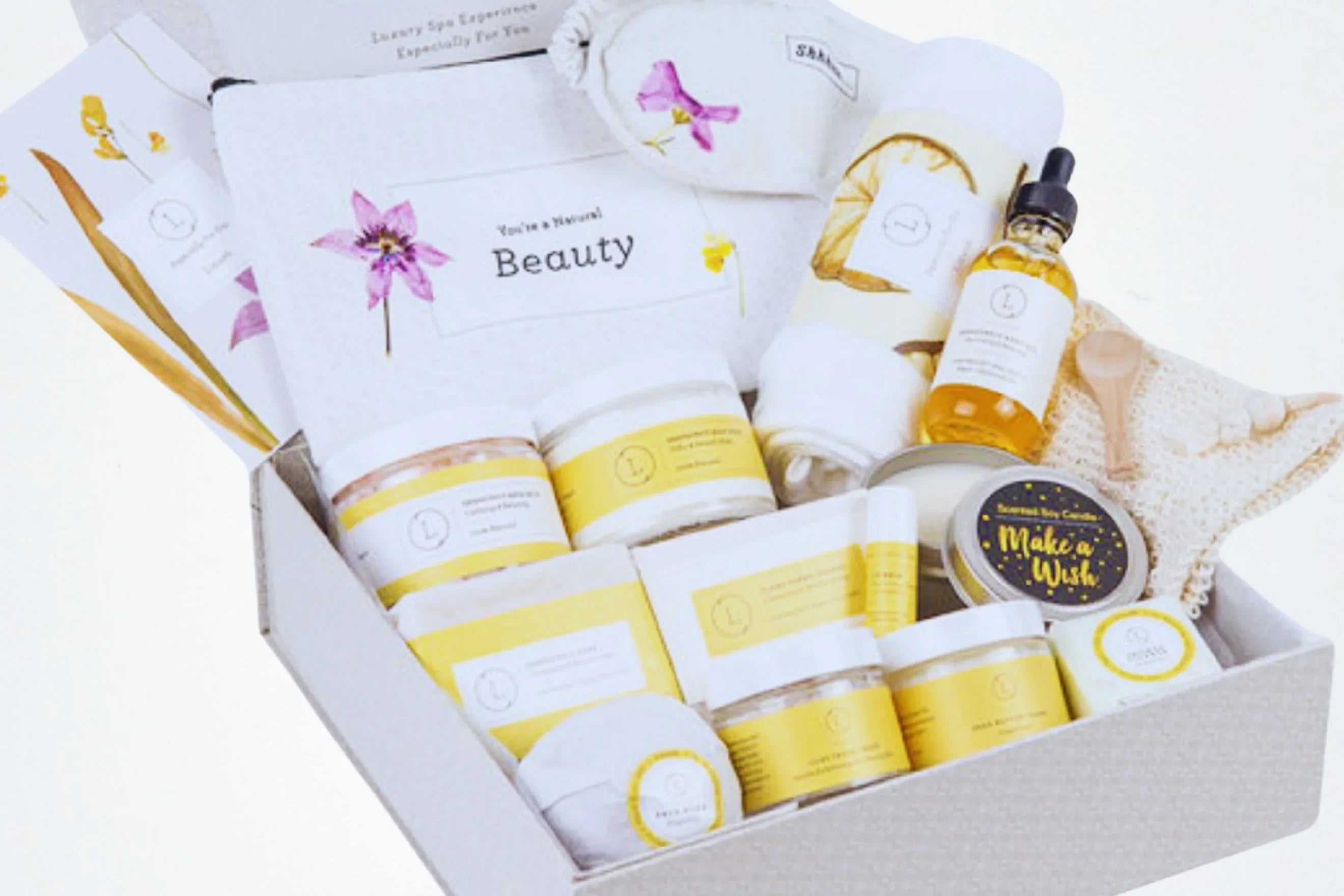 Luxury spa gift box with natural beauty products, cream jars, oils, towel, and wooden spoon