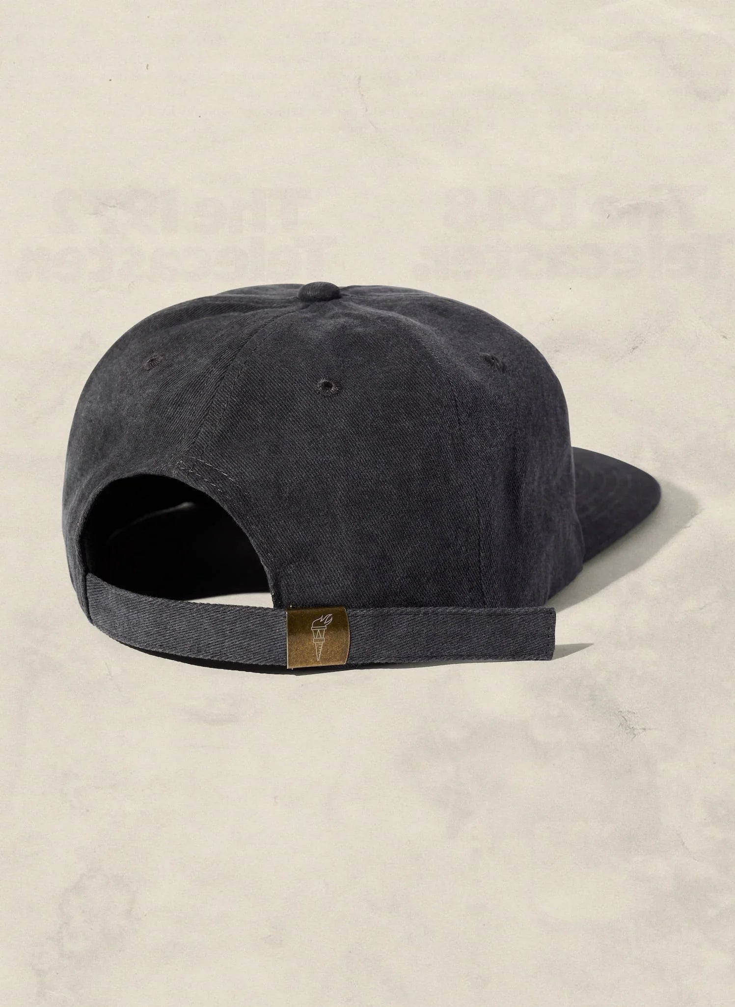 Dark gray adjustable cap with gold torch tag, displayed on neutral background at Qu!rk Boutique