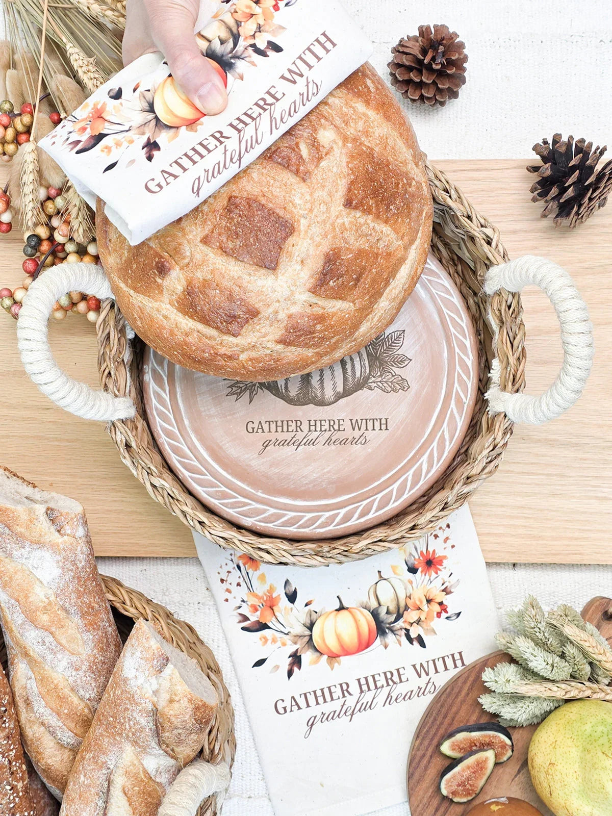 Freshly baked bread in woven basket with autumn-themed napkin and plate saying 'Gather here with grateful hearts'