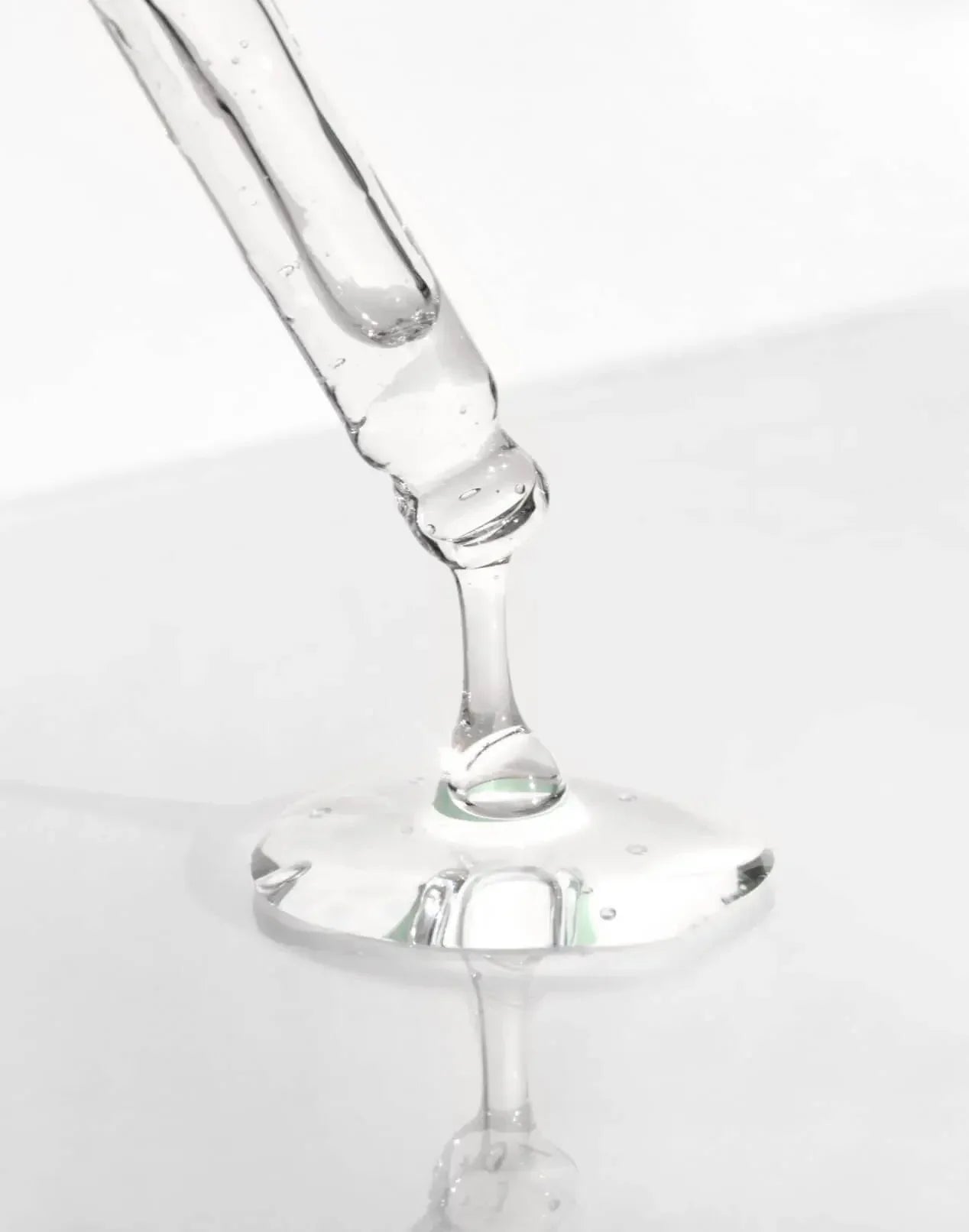 Clear serum dropper dripping liquid on white, ethical beauty product from Qu!rk Boutique
