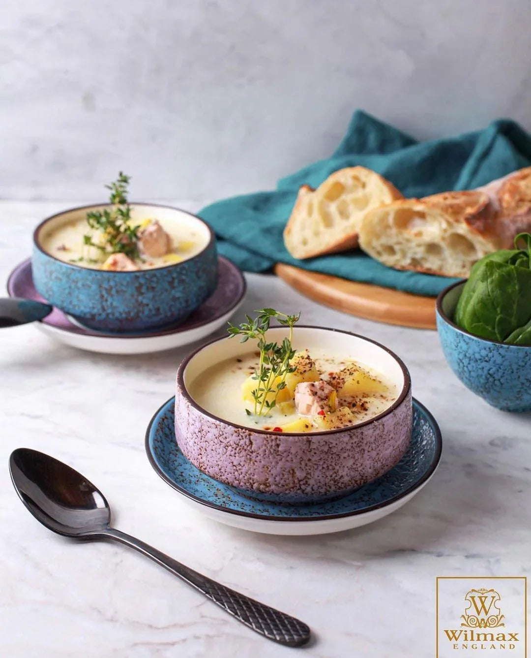 Artisan ceramic bowls with creamy soup, fresh herbs, and bread on marble table, styled for Qu!rk Boutique.