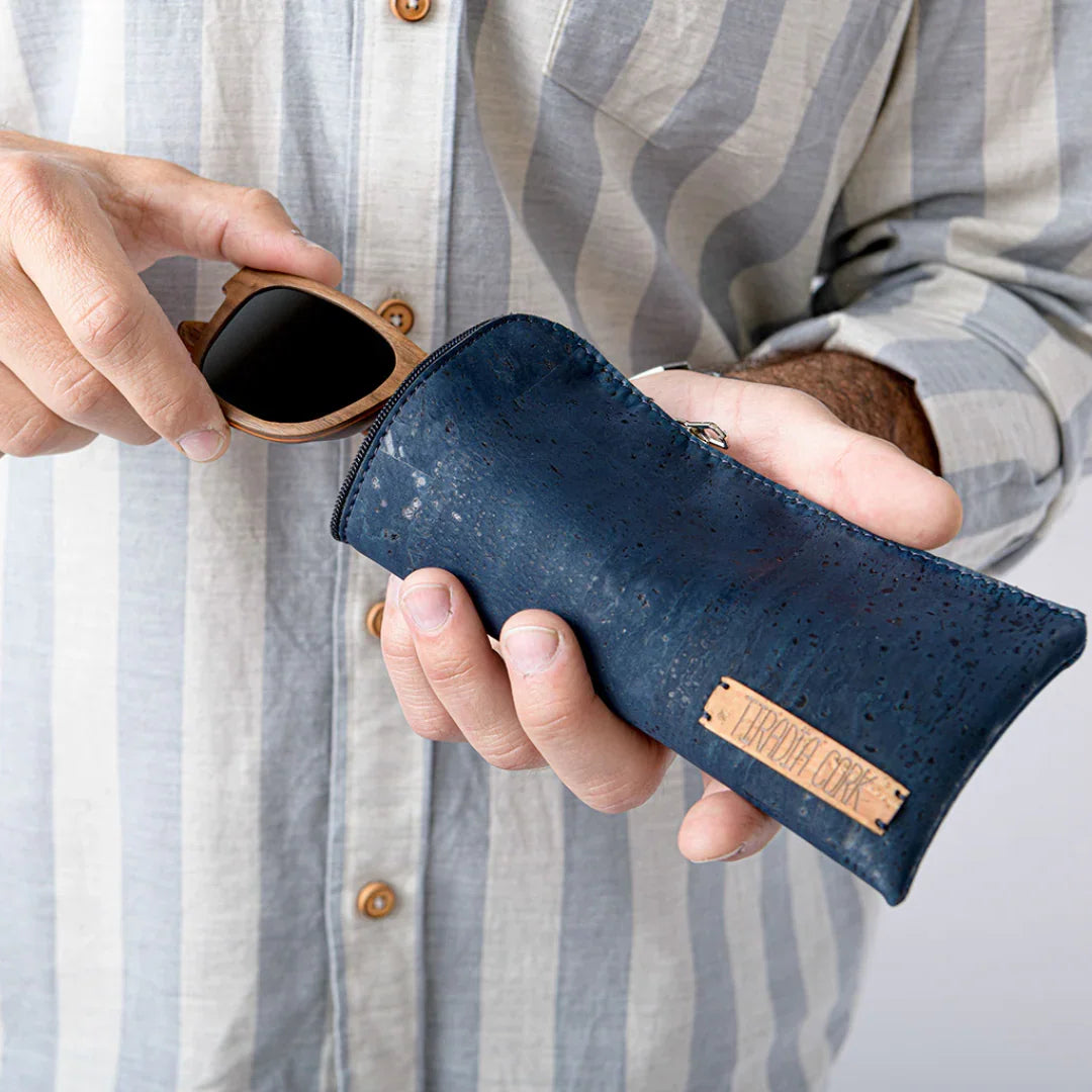 Person in striped shirt holding wooden sunglasses and blue eco-friendly case from Qu!rk Boutique