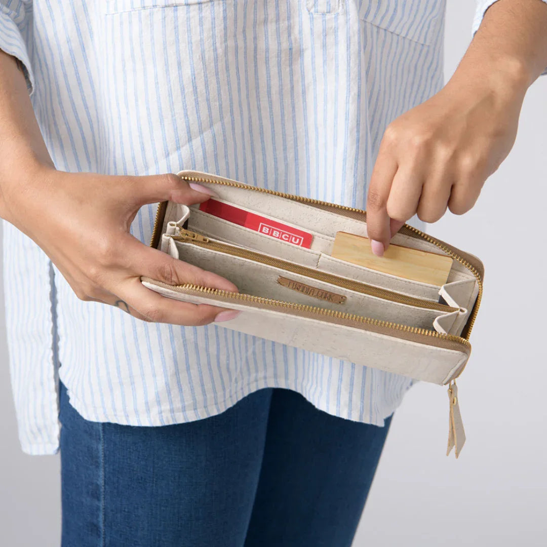 Person holding beige zippered wallet with cards, promoting sustainable accessories at Qu!rk Boutique.