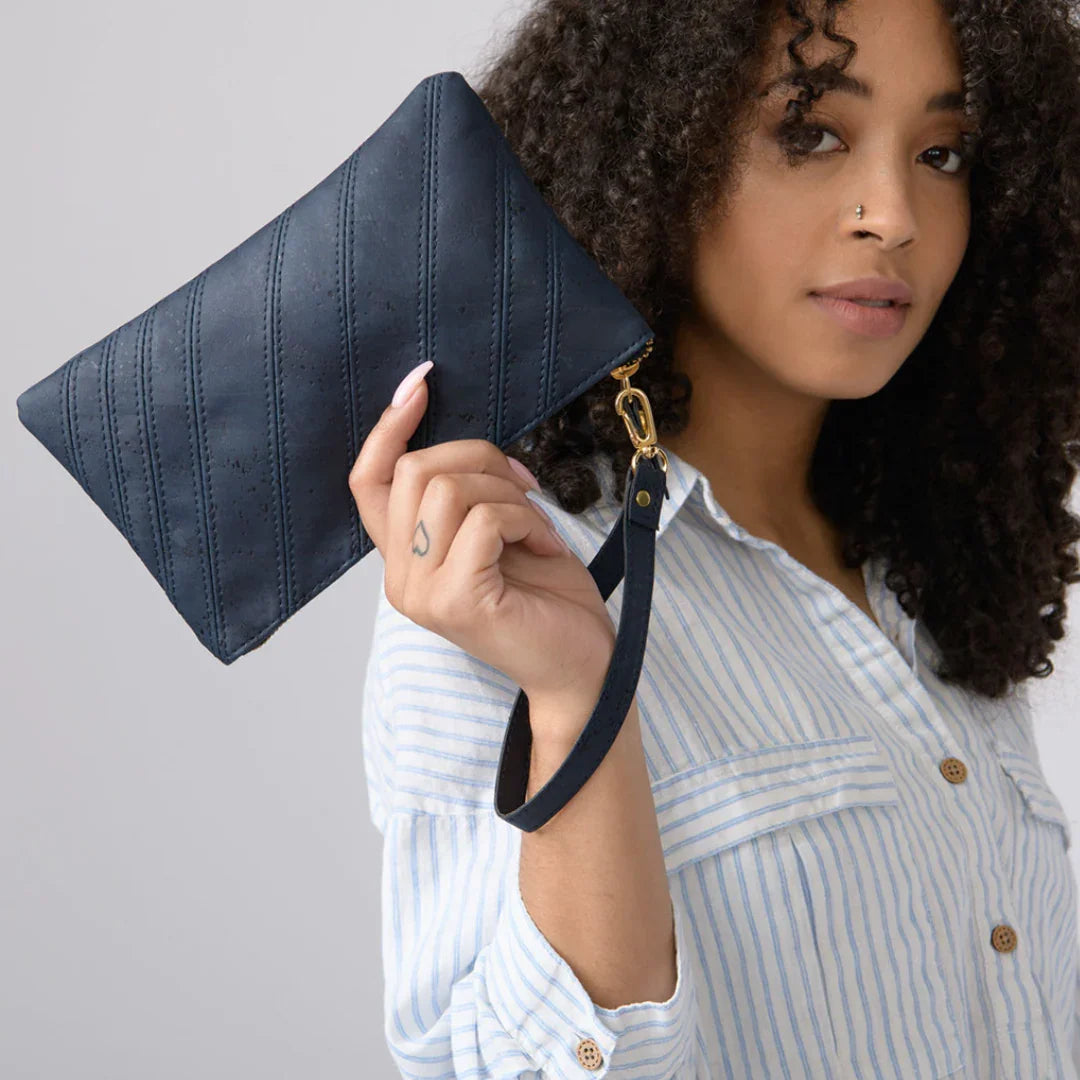Woman holding a navy blue eco-friendly wristlet bag, wearing a striped shirt, at Qu!rk Boutique