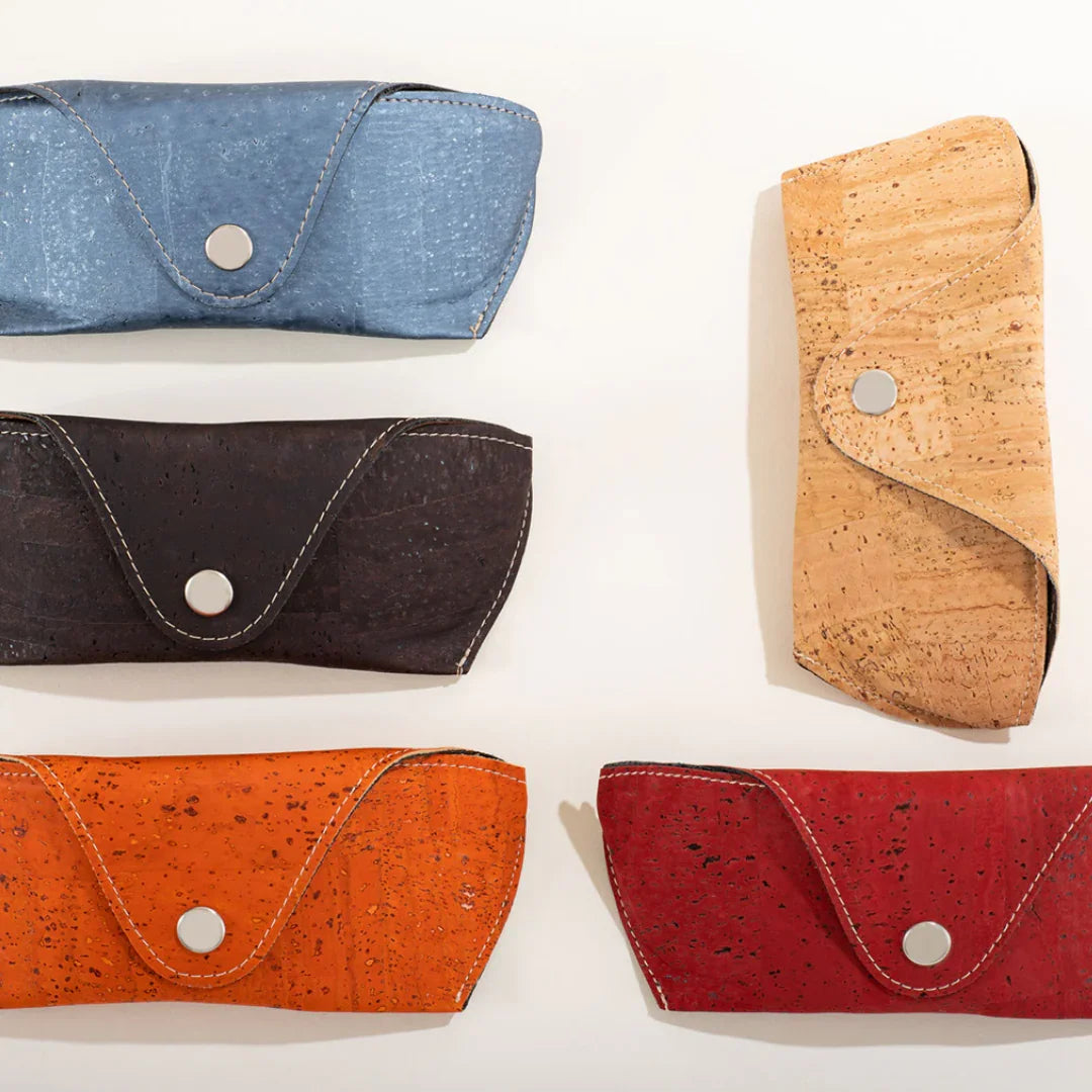 Five colorful cork eyeglass cases with snap closures on a light surface at Qu!rk Boutique.
