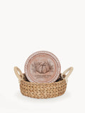 Decorative round terracotta plate with pumpkin and leaves illustration, in woven basket with rope handles