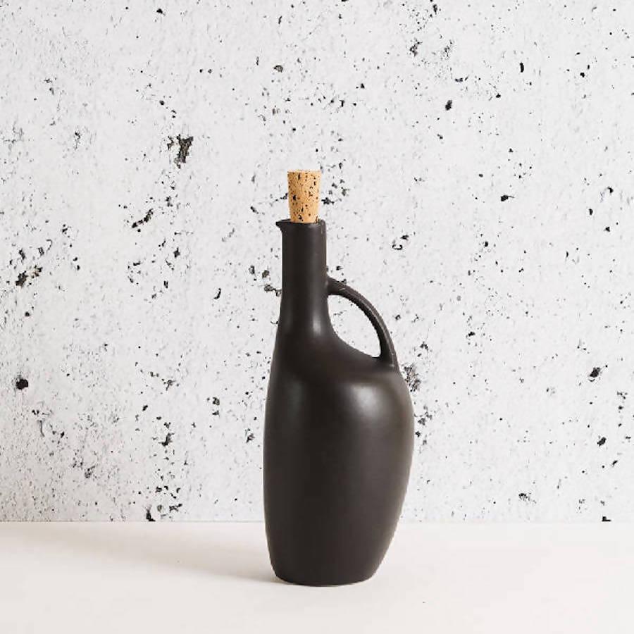 Modern black ceramic vase with cork stopper and handle on minimalist white speckled background