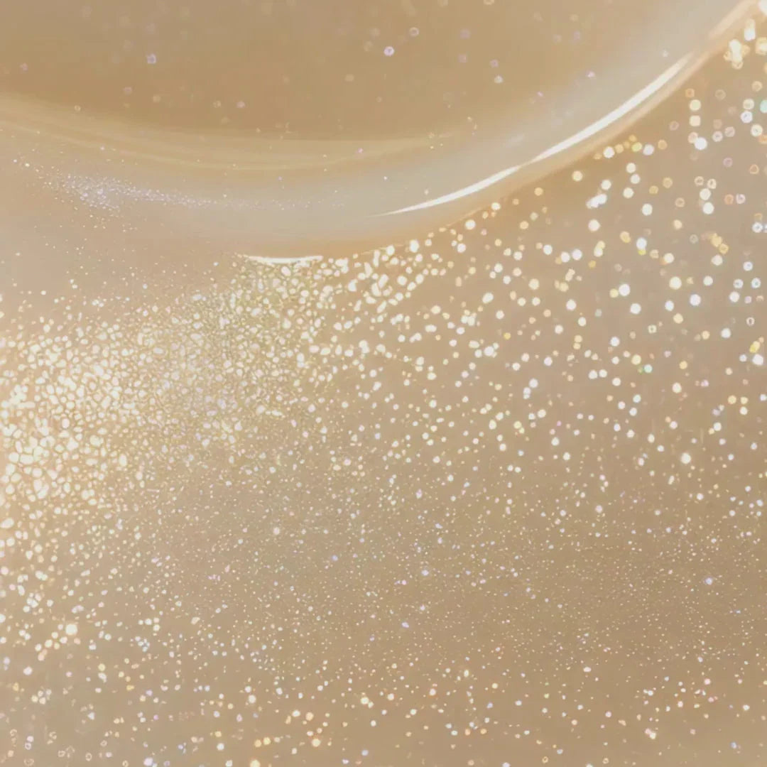 Glittering golden sparkles on a soft beige background, cosmic and festive winter shimmer.