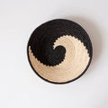 Ethically sourced woven basket with black and natural spiral pattern on white background
