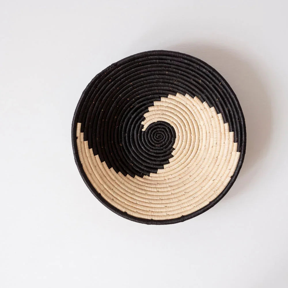 Ethically sourced woven basket with black and natural spiral pattern on white background