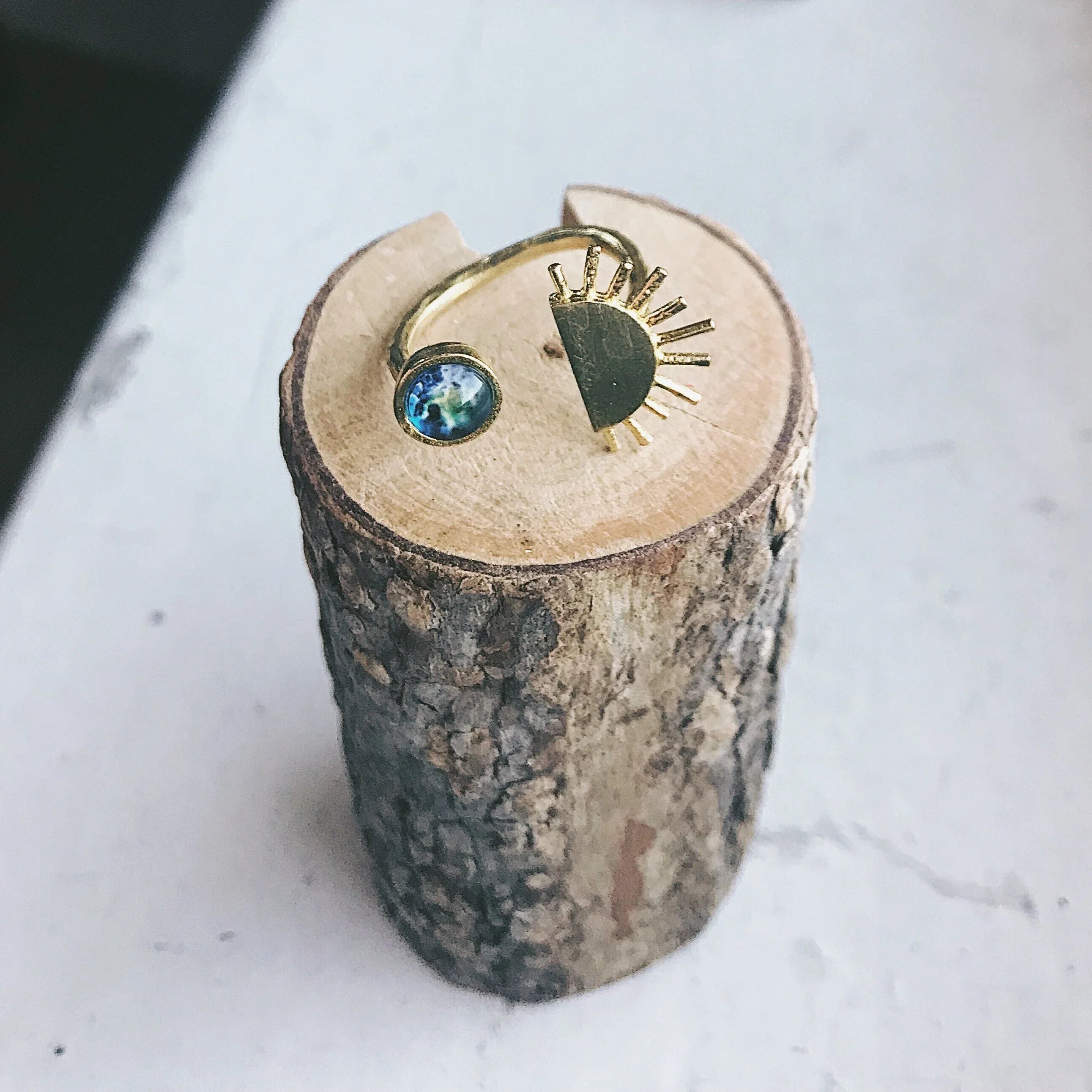 Gold sun and gemstone ring on wood display at Qu!rk Boutique, artist-designed jewelry