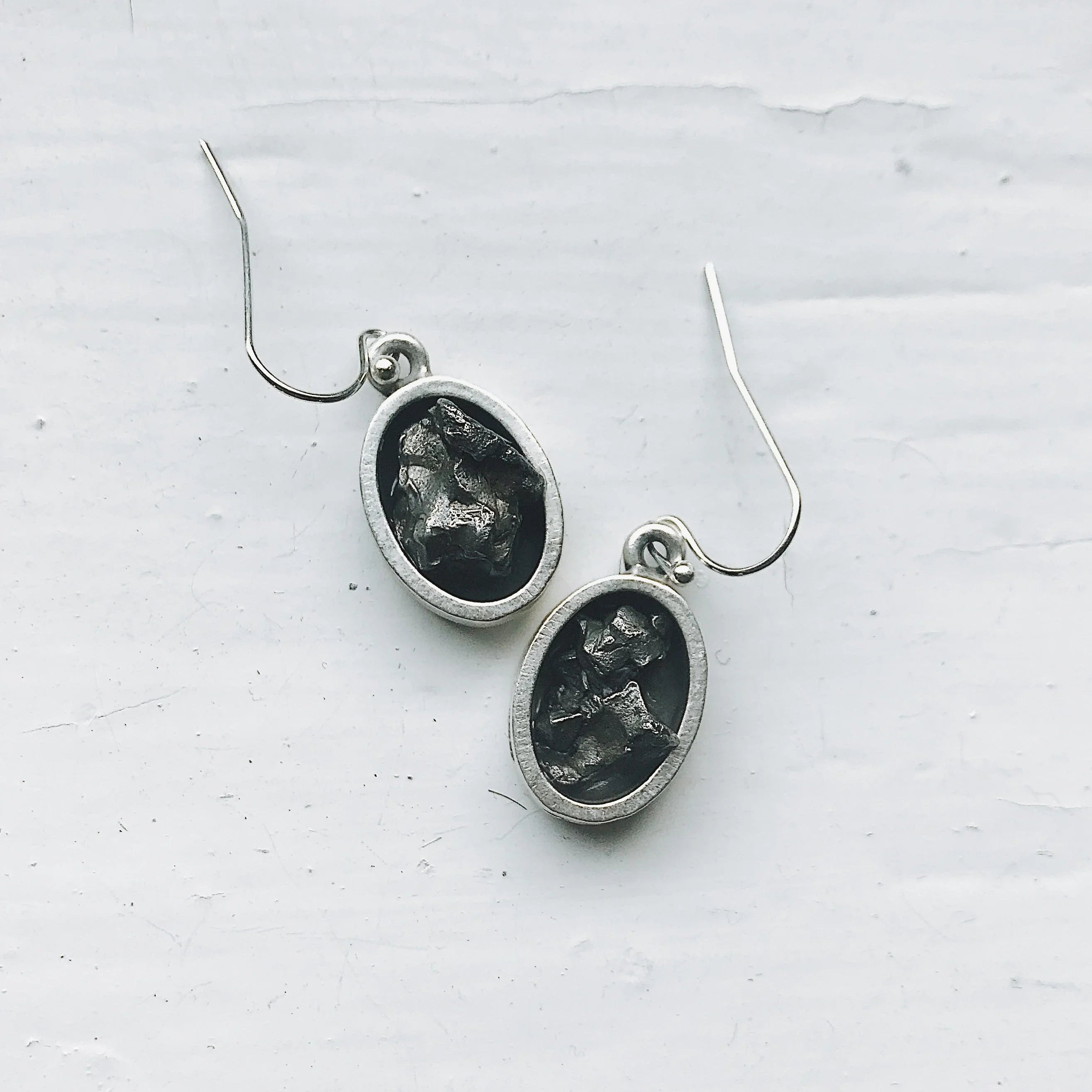 Oval silver dangle earrings with raw black stone, artisan jewelry at Qu!rk Boutique