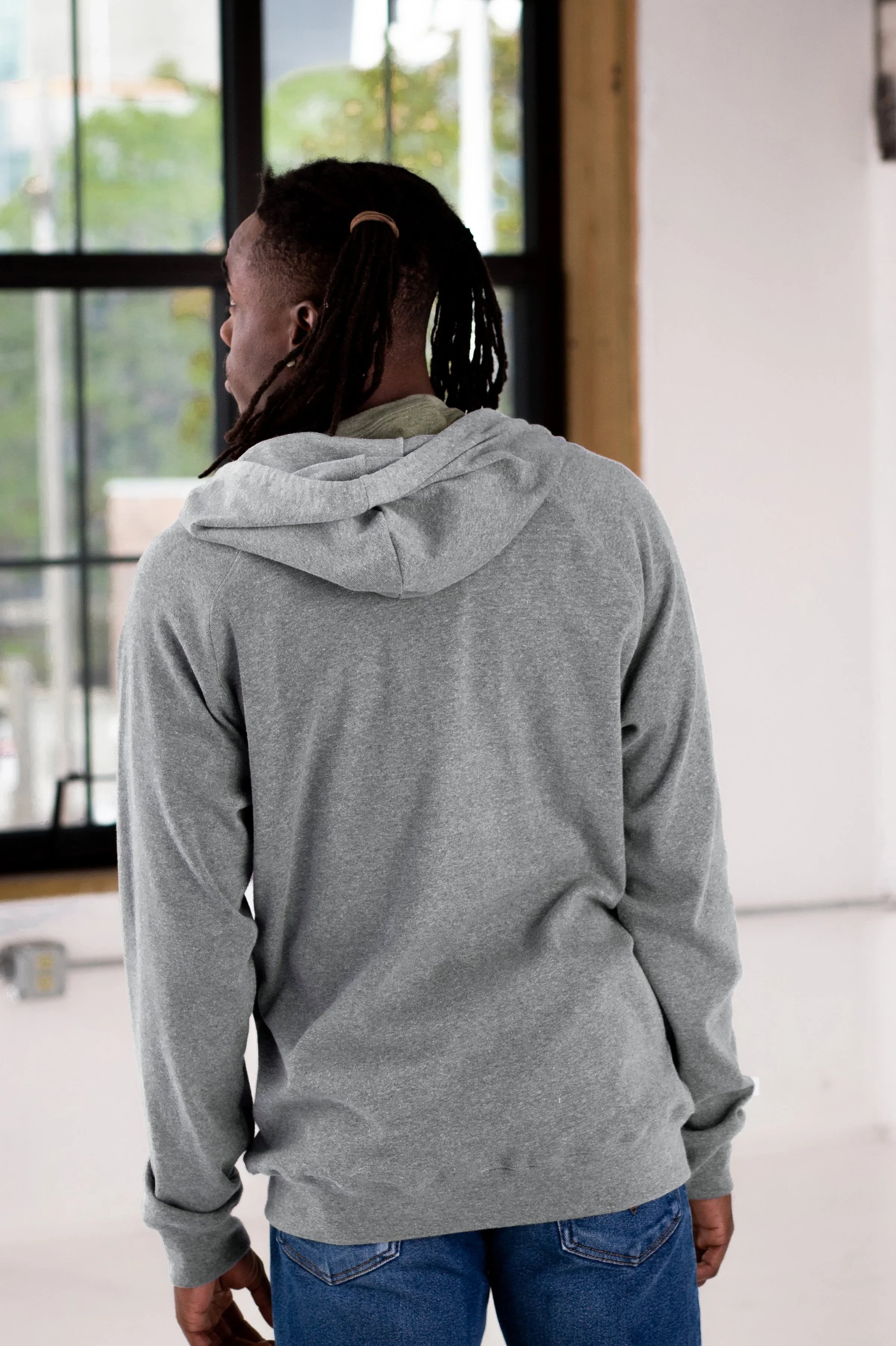 Person wearing a heather grey hoodie and jeans in a modern boutique studio setting