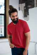 Man in red V-neck T-shirt and jeans, smiling indoors, showcasing Qu!rk Boutique style