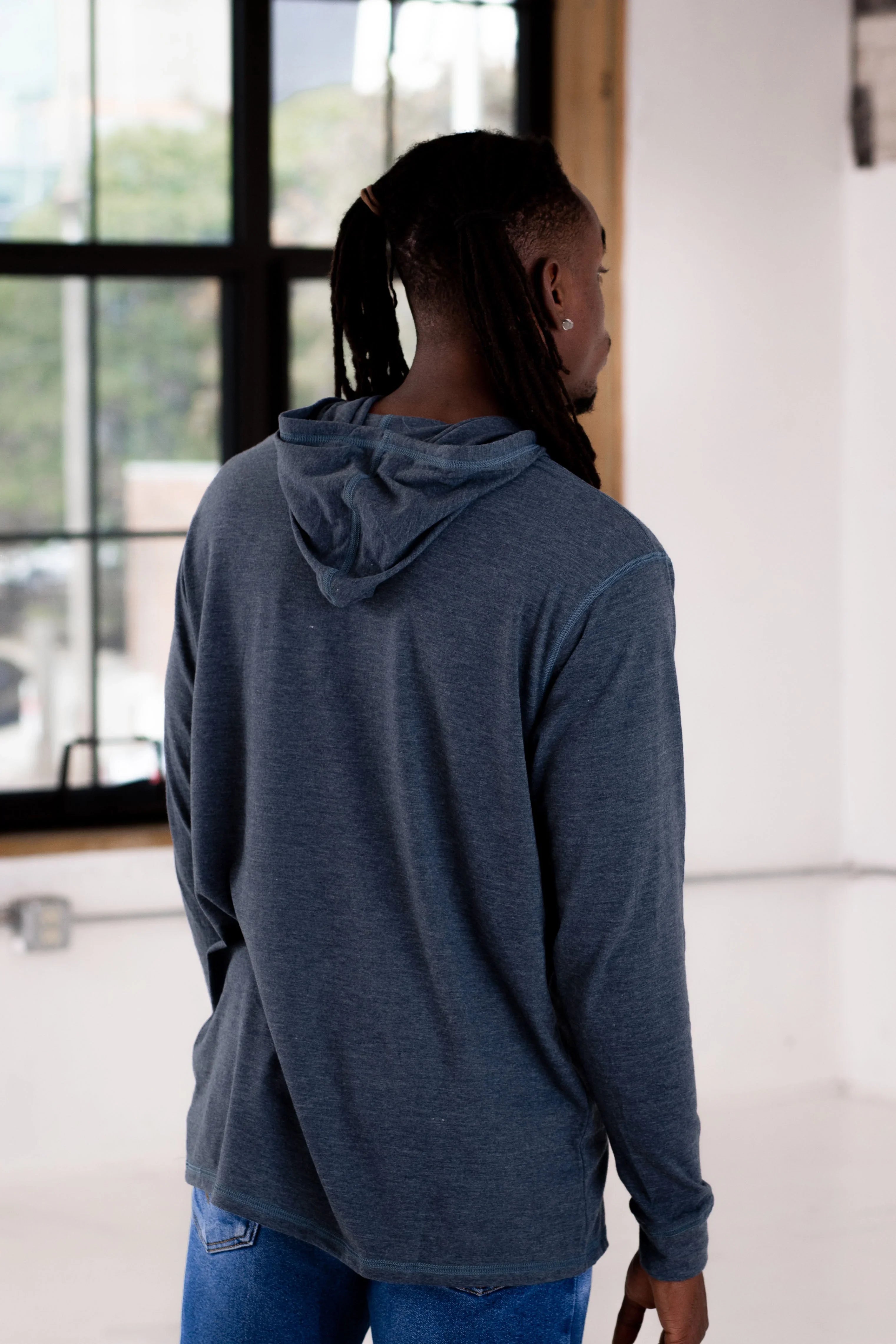Person wearing a navy blue long-sleeve hoodie in a modern boutique setting at Qu!rk